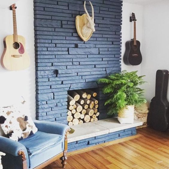 a cool midnight blue brick fireplace with logs inside and a potted plant is a lovely decor idea for any modern space