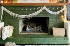 31 a green brick fireplace with lights and a garland, with decor, candles and artwork is a cool and lovely decoration