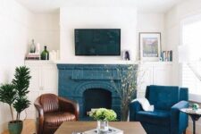 36 a mid-century modern living room with a blue brick fireplace, a brown leather chair and a navy one, a coffee table and some decor