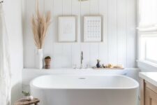 a beautiful boho bathroom with an oval tub, a beadboard wall, a wooden vanity, a fabric chandelier is very chic