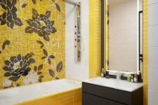 a beautiful modern bathroom clad with yellow skinny tiles, a floral tile accent wall, a floating black vanity and a lit up mirror is a lovely space