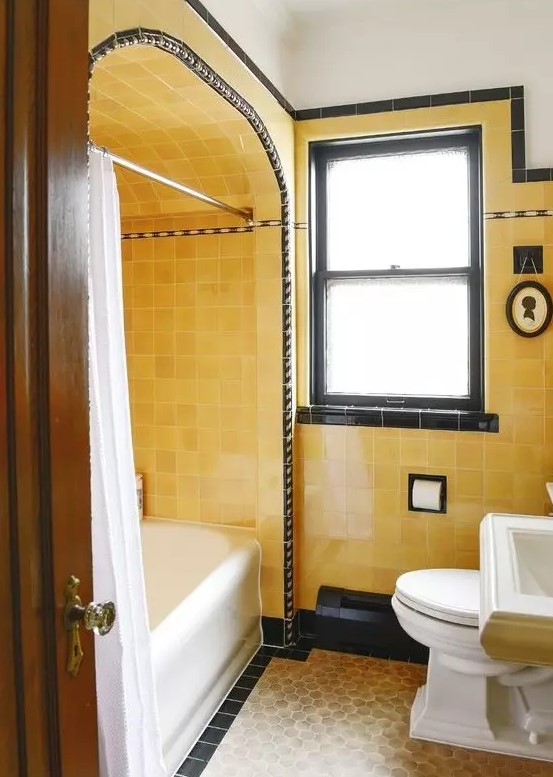 a bright vintage bathroom with yellow tiles, black touches for drama and white vintage appliances