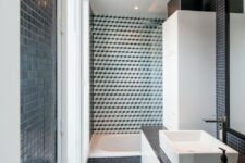 a contemporary black and white bathroom with a tub, some cabinetry, a window and cool tiles in the tub zone