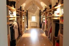 a large attic closet with open shelves and racks, rails and dressers can accomodate a lot of things, and built-in and pendant lights help to find everything you need