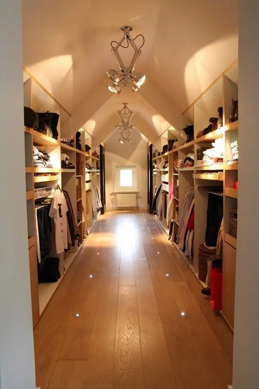 A large attic closet with open shelves and racks, rails and dressers can accomodate a lot of things, and built in and pendant lights help to find everything you need