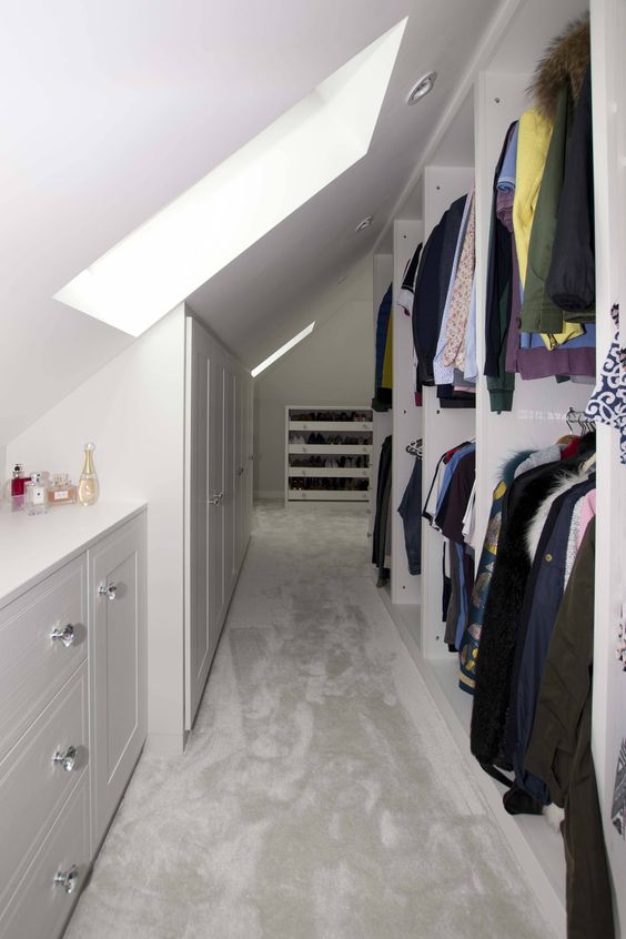A large white closet with open storage compartments, dressers and built in storage units, skylights and built in lights