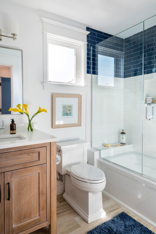 a modern farmhouse bathroom with a navy tiles and white ones, a stained vanity and some art and decor, a navy rug