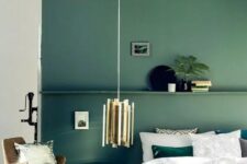 a muted green accent wall with a shelf and matching emerald bedding and a pillow