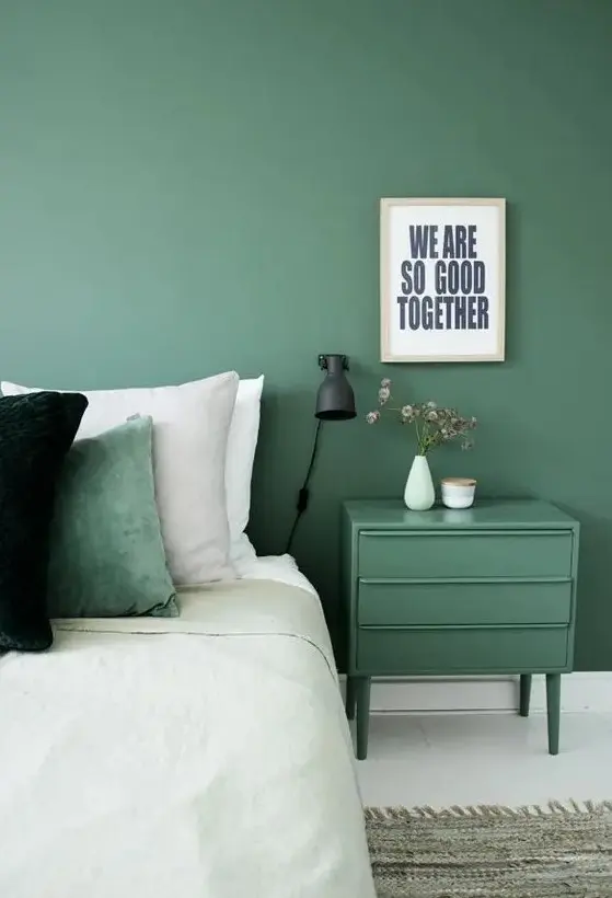 a muted green wall and a matching nightstand plus a matching pillow for relaxation and comfort
