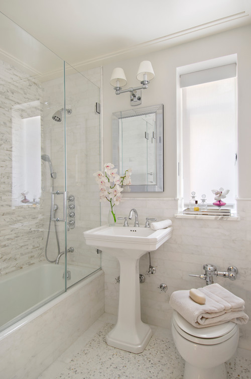 A neutral vintage bathroom with printed and non printed tiles, a tub, a pedestal sink and a toilet is lovely and cool
