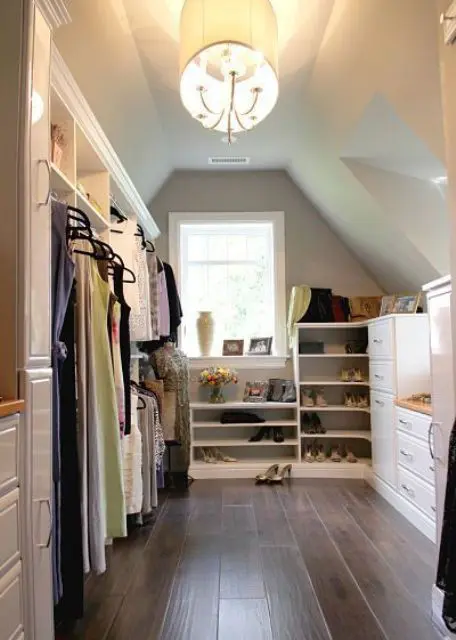 a small attci closet with dressers, open shelves and storage compartments, a cool chandelier and lots of natural light