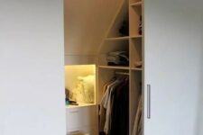 a small attic closet with open storage compartments and niches, with drawers and shelves, built-in lights and sliding doors