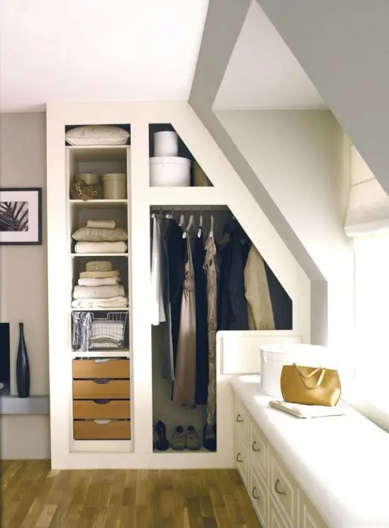 A small built in attic closet with open shelves, small drawers, railing for clothes and a bench at the window is a cool and functional idea