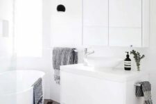 a small contemporary bathroom with a tub, a white floating vanity and a round sink, a large mirror and a shower