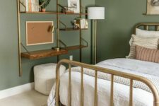 a welcoming bedroom with sage green walls, a brass bed with neutral bedding, a shelving unit with a desk