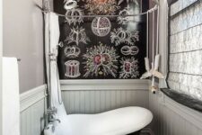a whimsy bathroom clad with grey plaks and with a catchy floor, a small black bathtub in vintage style and a catchy accent wall