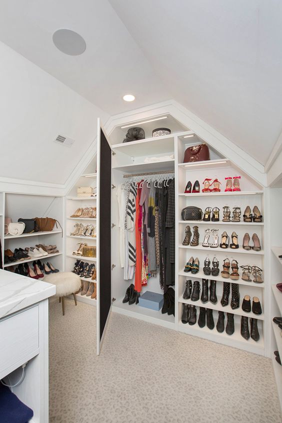 an attic closet with open shelves, a mirror and a dresser in the center of the closet is a lovely and smart space