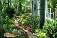 02 a whimsical fairy garden with greenery and bright blooms, trees and a stone path plus a bird bath is gorgeous