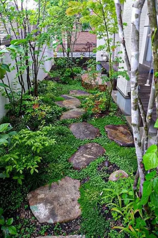 A small Japanese inspired side yard with rocks as pavements, greenery, shrubs and a couple of trees is very peaceful