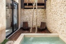 08 a minimal outdoor space with stone walls, a dark-stained furniture, a plunge pool, some trees and wooden chairs