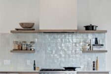 10 a contemporary stained kitchen with a light blue zellige tile backsplash, open shelves, wooden beams and a hood