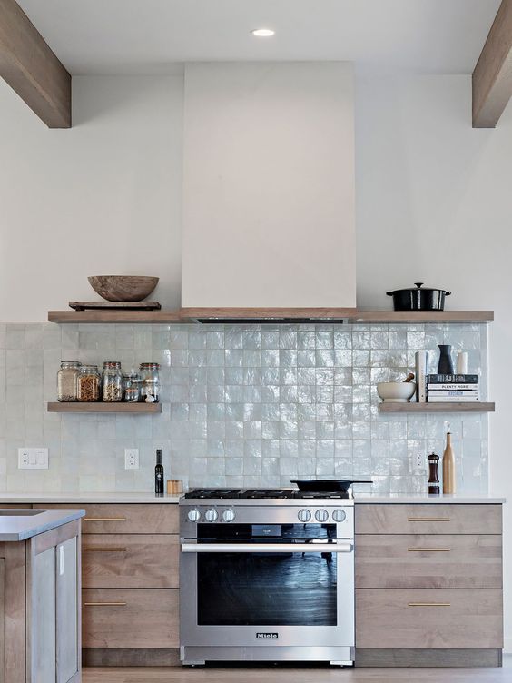 a contemporary stained kitchen with a light blue zellige tile backsplash, open shelves, wooden beams and a hood