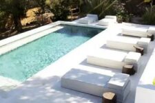 10 a minimalist backyard with a pool, antislip stone tiles that form a deck and steps, a series of loungers with stump side tables