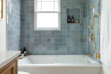 12 a modern bathroom with penny tiles and blue zellige ones around the tub, a timber vanity, gold and brass fixtures