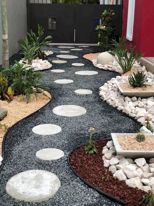 a stylish modern rock side yard with gravel and stepping stones, potted greenery and cacti is a cool space