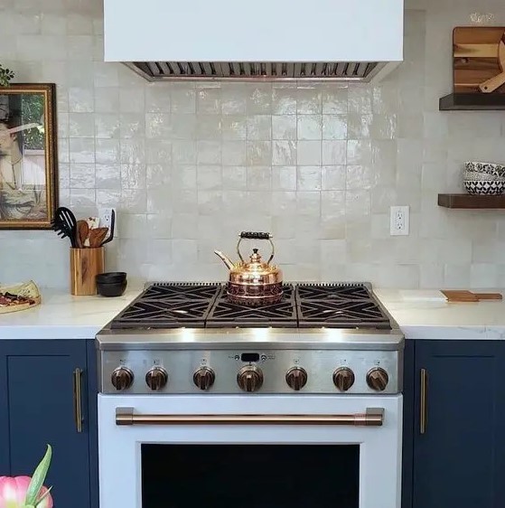 a fantastic navy kitchen with a white cooker and a hood plus fabulous mother of pearl zellige tiles for a soft touch