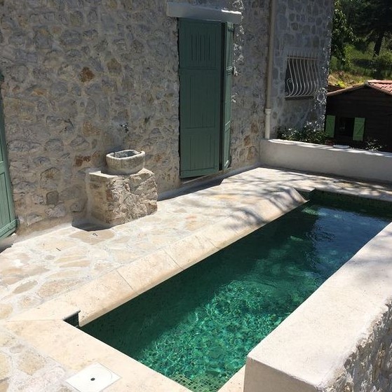 a small and rustic backyard done with stone and a narrow and long pool that will refresh you