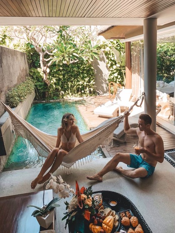 a small backyard pool surrounded with greenery, a with a wooden deck with loungers and a hammock is a perfect boho retreat