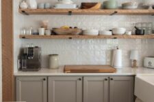 18 a modern farmhouse kitchen with grey shaker cabinets, white stone countertops, a white zellige tile backsplash and open shelves