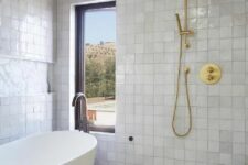 19 a neutral bathroom with white Zellige tiles and geometric ones, an oval tub and brass and gold fixtures