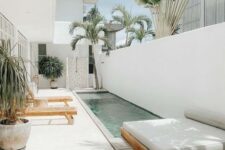 19 an all-white outdoor space with a deck, loungers, a daybed, a long and narrow pool and some potted trees is amazing