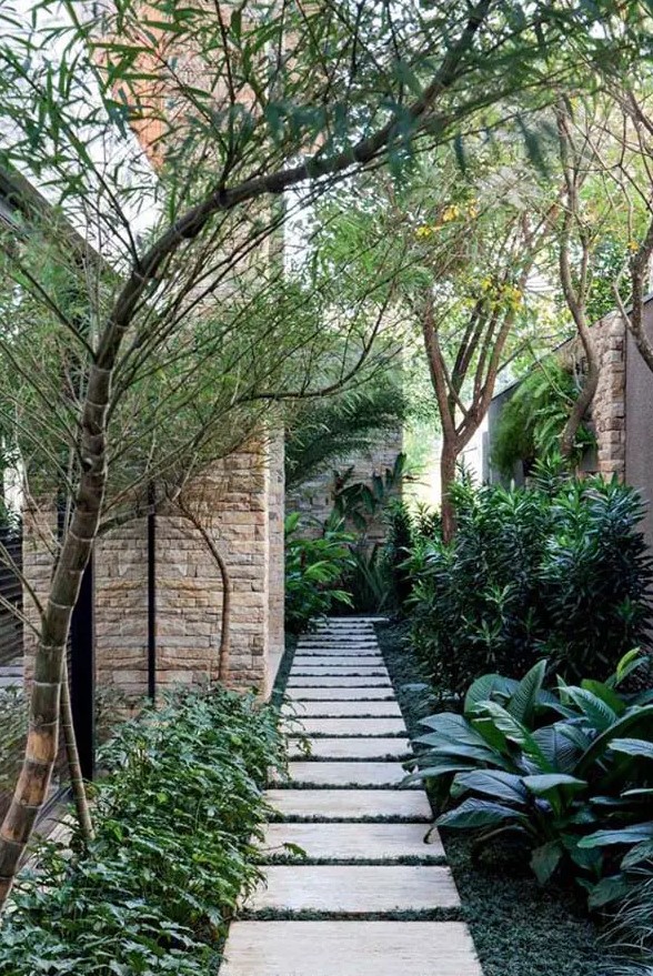 a beautiful and harmonious side yard with greenery, pavements, some trees is a peaceful and shadow-covered space