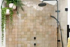25 an attic shower space clad with blush and tan zellige tiles, with suspended potted plants and black fixtures for a modern feel
