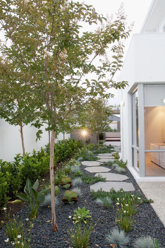a contemporary side yard with pebbles, irregular pavements, greenery and trees plus some blooms is awesome