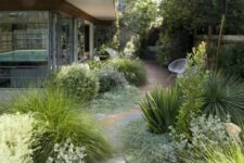 28 a cool and textural side yard with a wooden deck and irregular stone paths, lots of greenery and grasses for a catchy look