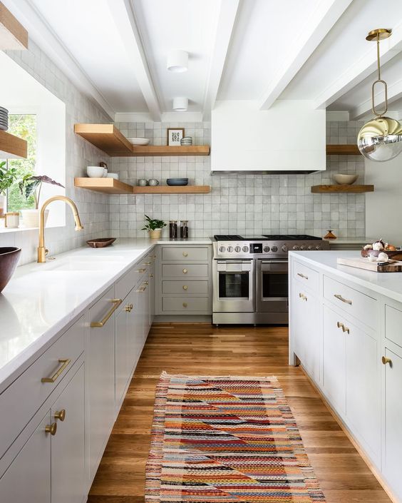 a refined neutral mid-century modern kitchen with a grey zellige tile backsplash, white stone countertops, a hood and open shelves