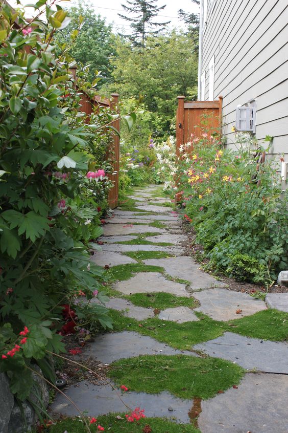 a cozy cottage-style side yard with an irregular stone path, greenery and blooms is a cool and lovely nook