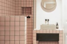 32 a catchy modern bathroom with pink square tiles, a terrazzo floor, a vanity clad with tiles and a round mirror