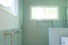 33 a catchy pastel green bathroom with square tiles and a shower space, a white vanity, a couple of windows to let natural light in