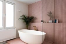 35 a contemporary bathroom with mauve square tiles, a shower space and an oval tub, a shelf and some decor and greenery