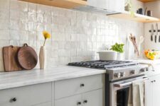 35 a modern grey kitchen with a zellige tile backsplash, open shelves, a hood and black knobs for a catchy detail