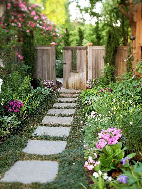 a lovely flourishing side yard with a green lawn, lots of greenery and bright blooms is a cool secret garden space