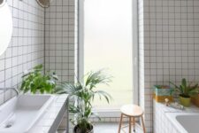 39 a light-filled bathroom with white square tiles, a tub clad with tiles, a vanity clad with them, too, some potted greenery