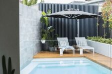 40 a modern backyard with a wooden deck, a plunge pool, some greenery and potted plants, loungers and an umbrella