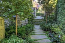 41 a lush and beautiful side yard with an irregular stone path, greenery and grasses and some trees plus lights along the path