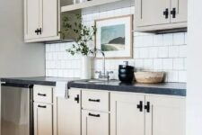 43 a greige kitchen with a white square tile backsplash, open shelves, and black countertops is a stylish space with a farmhouse feel